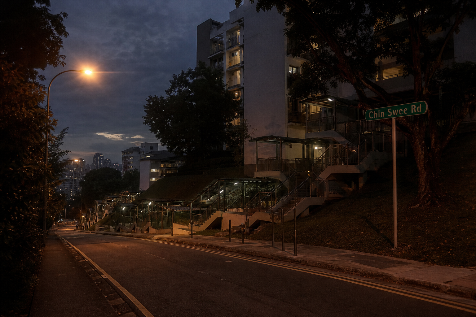 Chin Swee Road at dusk — asphalt, stair flights, and amber streetlight against a darkening sky